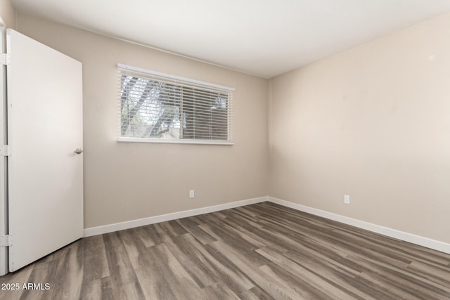 spare room featuring baseboards and wood finished floors