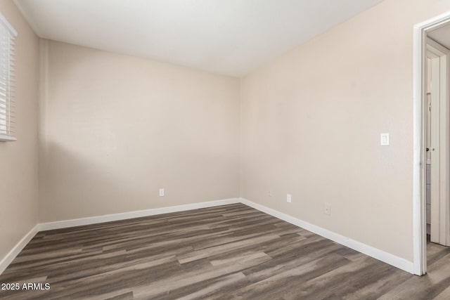 unfurnished room featuring baseboards and dark wood finished floors