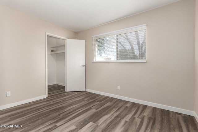 unfurnished bedroom featuring dark wood-style floors, baseboards, and a closet