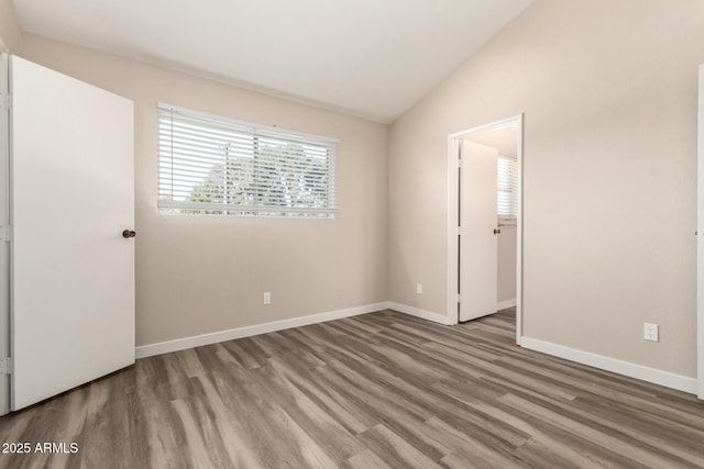 unfurnished bedroom featuring baseboards, vaulted ceiling, and wood finished floors