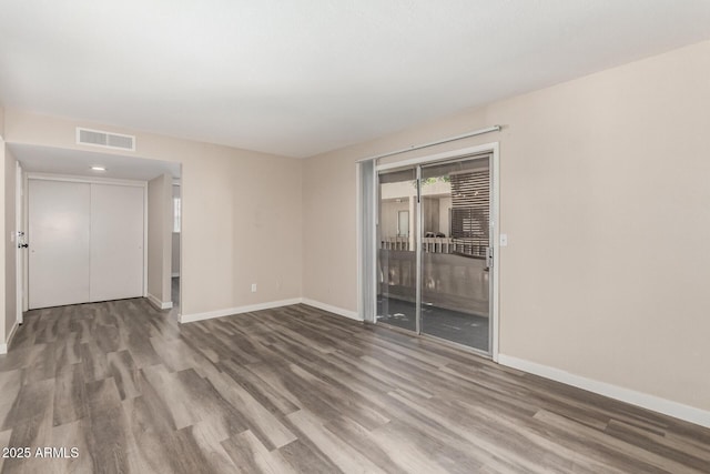 spare room featuring visible vents, baseboards, and wood finished floors