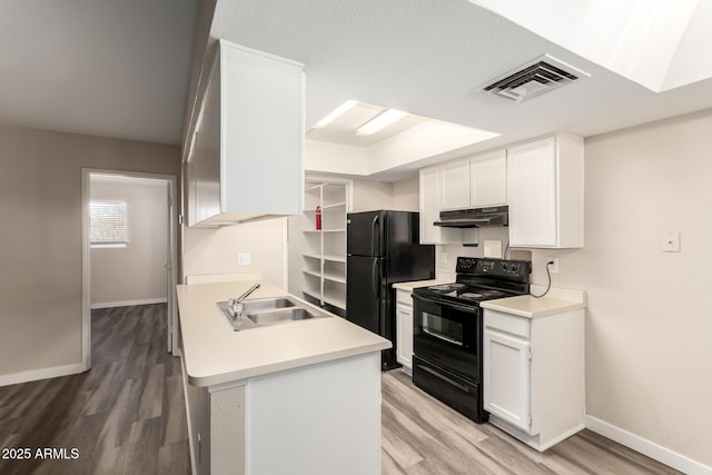 kitchen featuring visible vents, white cabinets, a sink, under cabinet range hood, and black appliances