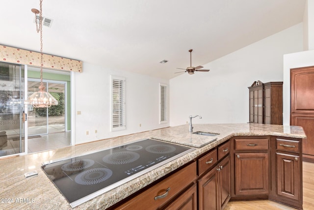 kitchen featuring black electric stovetop, ceiling fan with notable chandelier, vaulted ceiling, sink, and hanging light fixtures