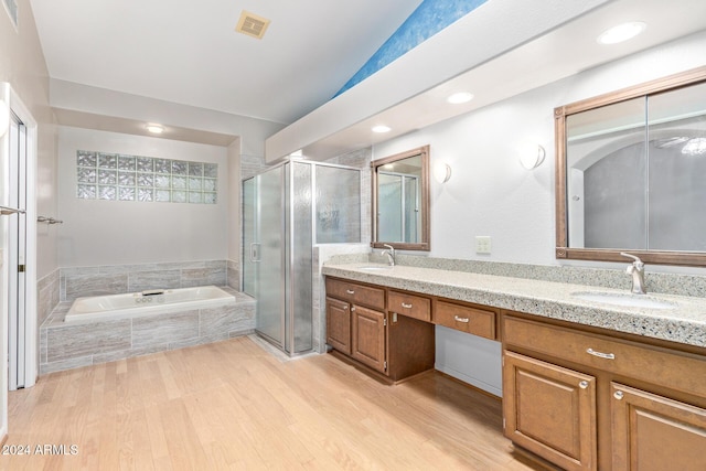 bathroom featuring hardwood / wood-style flooring, vanity, shower with separate bathtub, and vaulted ceiling