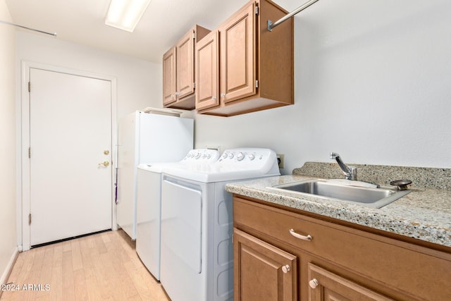 laundry area with cabinets, independent washer and dryer, sink, and light hardwood / wood-style flooring