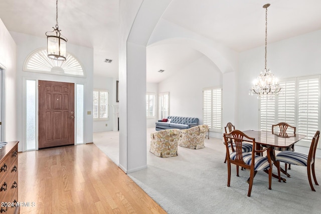 carpeted foyer with lofted ceiling and a notable chandelier