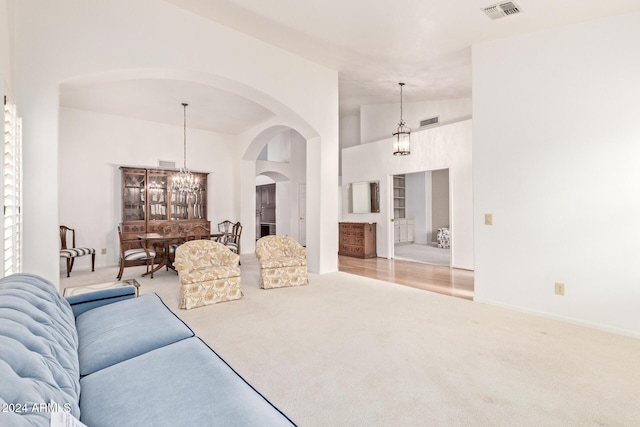 carpeted living room with a chandelier and vaulted ceiling