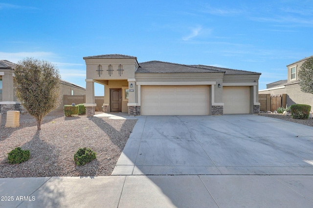 prairie-style home with fence, concrete driveway, stucco siding, a garage, and stone siding