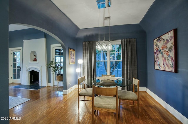 dining area with hardwood / wood-style floors, a notable chandelier, and vaulted ceiling