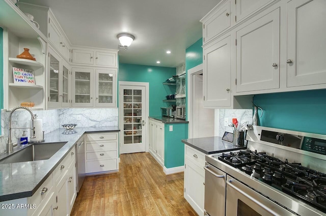 kitchen with stainless steel appliances, light hardwood / wood-style floors, white cabinetry, and sink