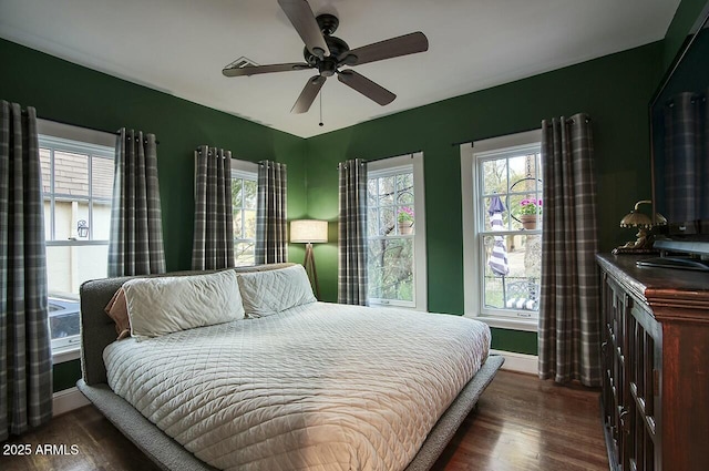 bedroom with ceiling fan, dark wood-type flooring, and multiple windows