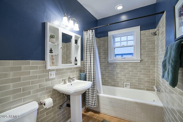 full bathroom featuring shower / bath combination with curtain, sink, tile walls, toilet, and hardwood / wood-style flooring