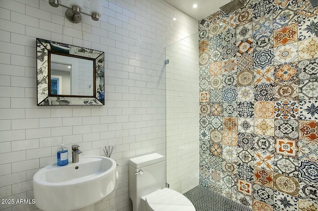 bathroom with toilet, tile walls, and sink