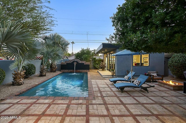 view of pool featuring pool water feature, an outdoor fire pit, a patio area, and an outdoor structure