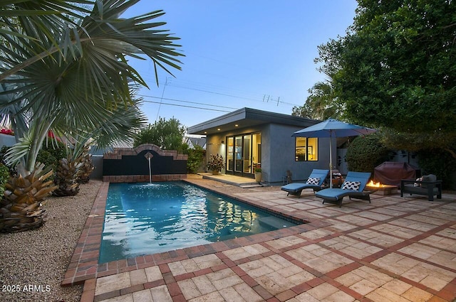 view of swimming pool featuring pool water feature, a patio, and a fire pit