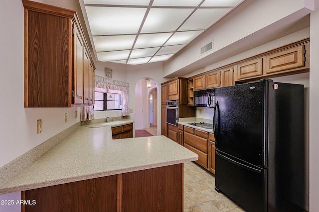 kitchen featuring visible vents, arched walkways, a sink, light countertops, and black appliances