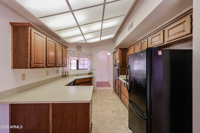 kitchen with visible vents, freestanding refrigerator, wall oven, light countertops, and a sink