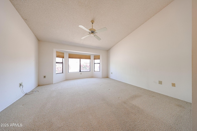 empty room with carpet flooring, a textured ceiling, a ceiling fan, and vaulted ceiling
