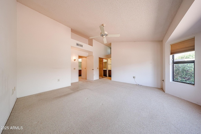 spare room with ceiling fan, light colored carpet, a textured ceiling, lofted ceiling, and visible vents
