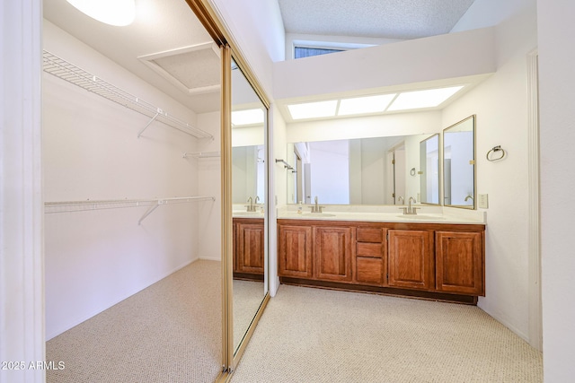 full bathroom with double vanity, a walk in closet, and a sink
