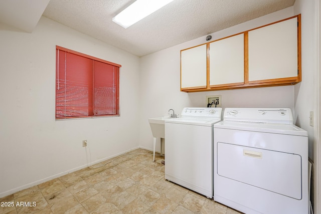 washroom with a textured ceiling, baseboards, cabinet space, and washing machine and clothes dryer
