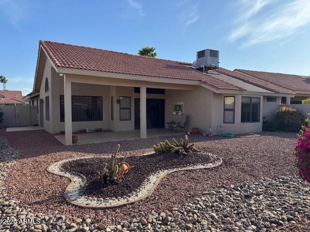 rear view of house featuring a tiled roof, a patio area, central AC, fence, and stucco siding