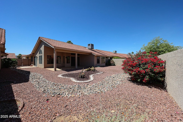 back of property with a fenced backyard, a patio, stucco siding, and a tile roof