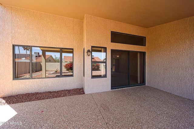 entrance to property with a patio and stucco siding