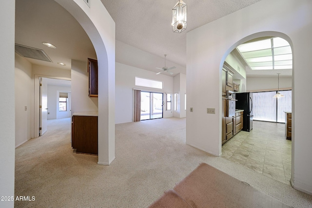 hall with light colored carpet, arched walkways, and visible vents
