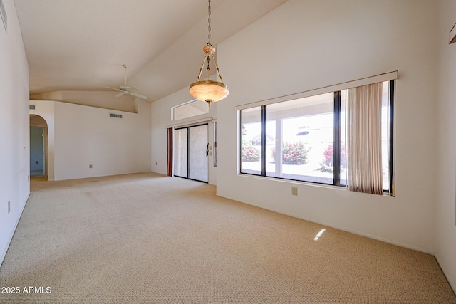 empty room featuring visible vents, ceiling fan, light carpet, and high vaulted ceiling