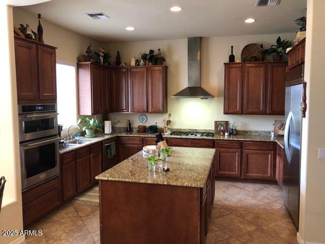 35401 N Via Tramonto St, Phoenix, AZ 85086 - kitchen with wall chimney range hood, stainless steel appliances, a kitchen island, light stone countertops, and recessed lighting