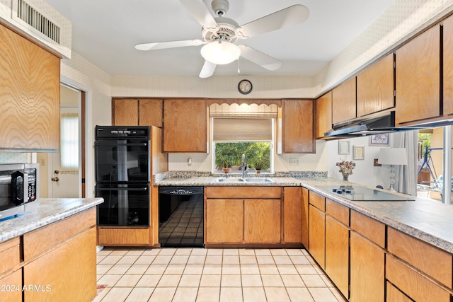 kitchen with brown cabinets, black appliances, light countertops, and a sink