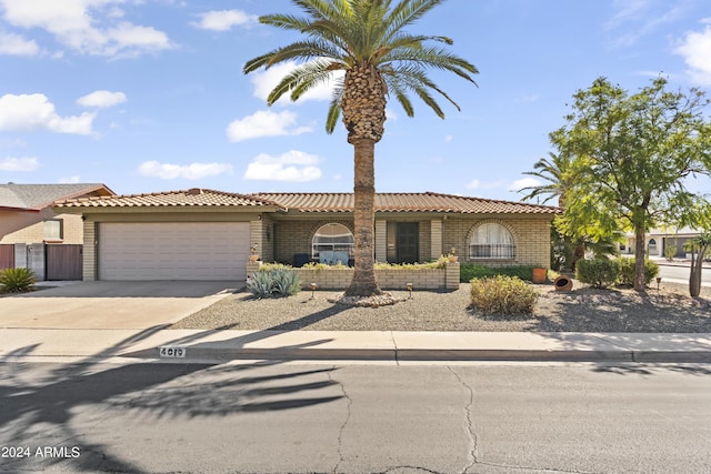 mediterranean / spanish home with a tiled roof, an attached garage, concrete driveway, and stucco siding