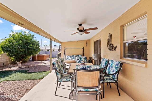 view of patio / terrace featuring ceiling fan, outdoor dining space, fence, and a hot tub