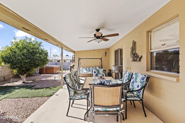 view of patio featuring a ceiling fan, a hot tub, a fenced backyard, and outdoor dining space