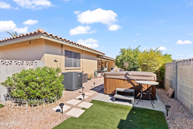 exterior space with central AC unit, a patio area, a fenced backyard, and a hot tub