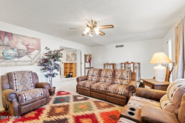 living area featuring ceiling fan, visible vents, a textured ceiling, and light colored carpet