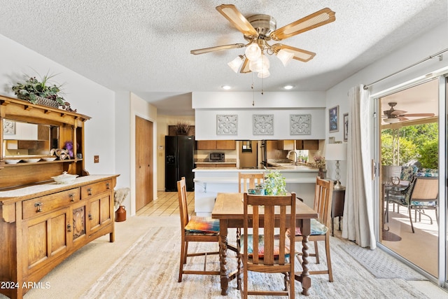 dining room with light colored carpet, ceiling fan, and a textured ceiling