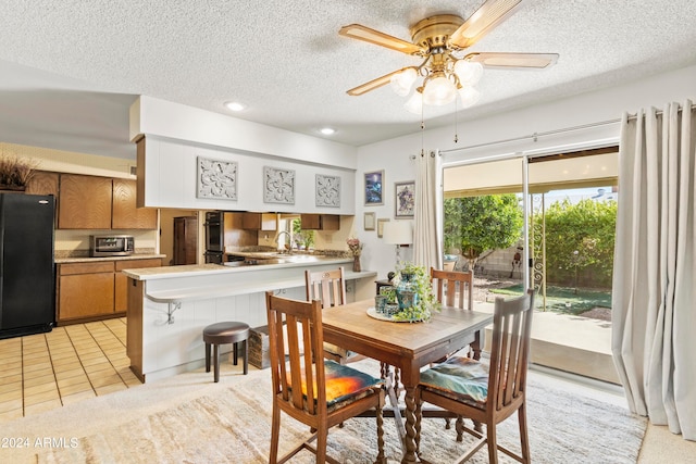 dining area featuring light tile patterned floors, ceiling fan, and a textured ceiling