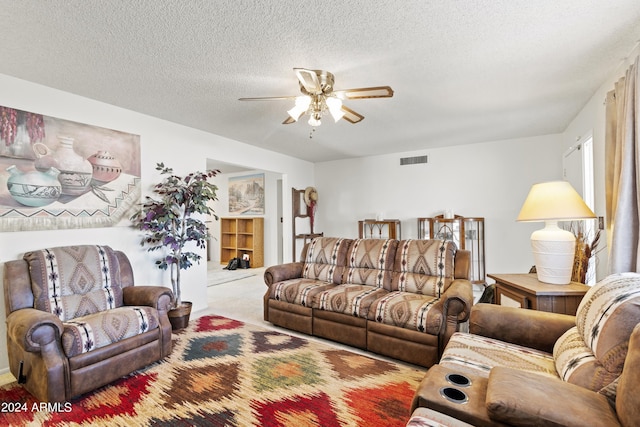 living area featuring carpet floors, ceiling fan, a textured ceiling, and visible vents