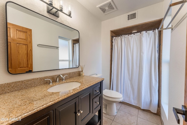 bathroom featuring tile patterned flooring, vanity, toilet, and walk in shower