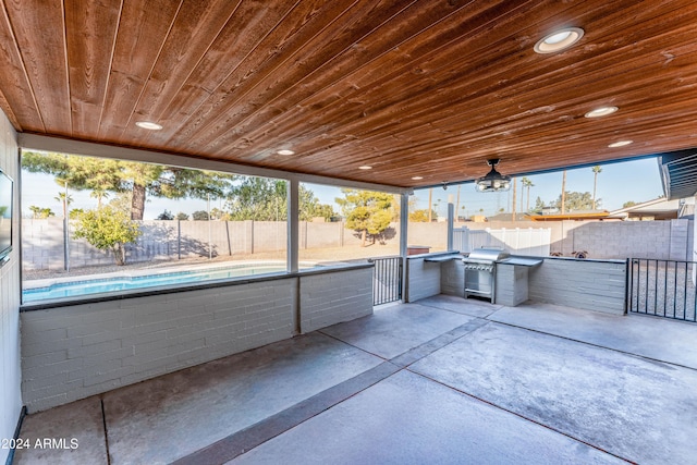 view of patio / terrace featuring a fenced in pool, area for grilling, and exterior kitchen