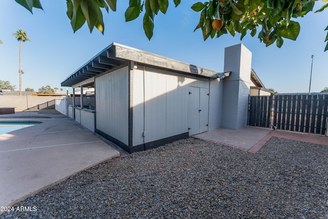 view of side of home featuring a patio and a fenced in pool