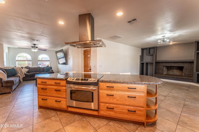 kitchen featuring ceiling fan, a brick fireplace, island exhaust hood, stainless steel electric stove, and light tile patterned floors