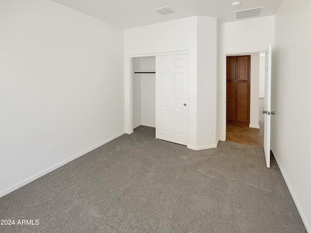 unfurnished bedroom featuring dark colored carpet and a closet