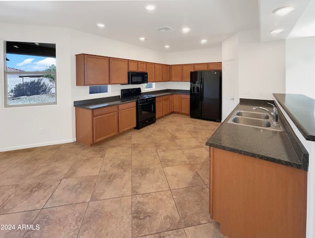 kitchen featuring dark stone counters, black appliances, and sink