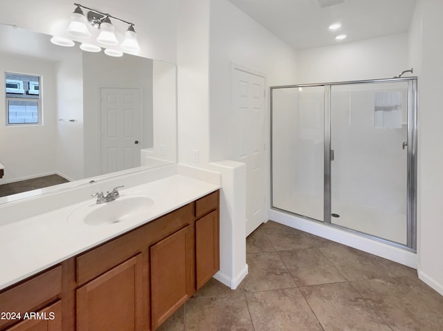 bathroom with walk in shower, vanity, and tile patterned flooring