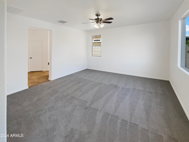 carpeted spare room featuring an AC wall unit, a wealth of natural light, and ceiling fan