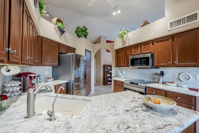 kitchen featuring backsplash, light stone counters, sink, and stainless steel appliances