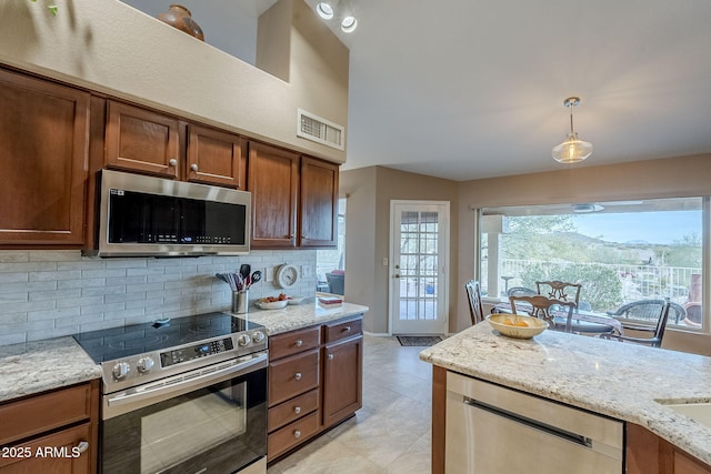 kitchen featuring hanging light fixtures, tasteful backsplash, light stone counters, a mountain view, and appliances with stainless steel finishes